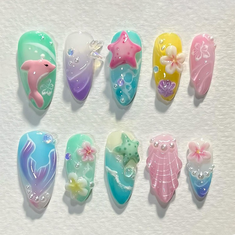 Cute mermaid-inspired press-on nails featuring 3D dolphins, starfish, seashells, and tropical flowers. Reusable fake nails perfect for summer beach vacations looks.