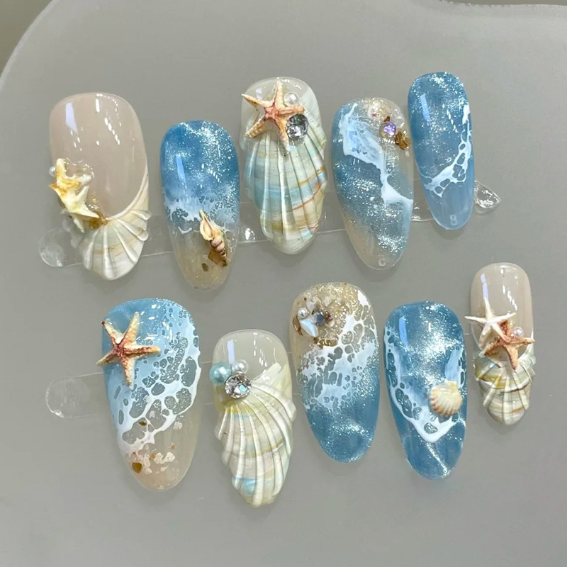 Luxury ocean press-on nails with 3D seashells, starfish, pearls, and blue wave designs. Reusable glossy nails perfect for beach vacations.