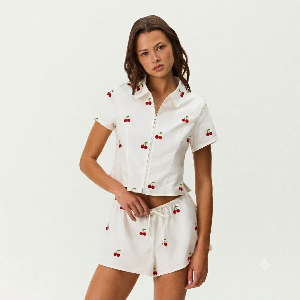 Featuring playful red cherry on a crisp white backdrop,a modern zip-front top,and comfortable drawstring shorts—perfect for garden picnics and seaside getaways.