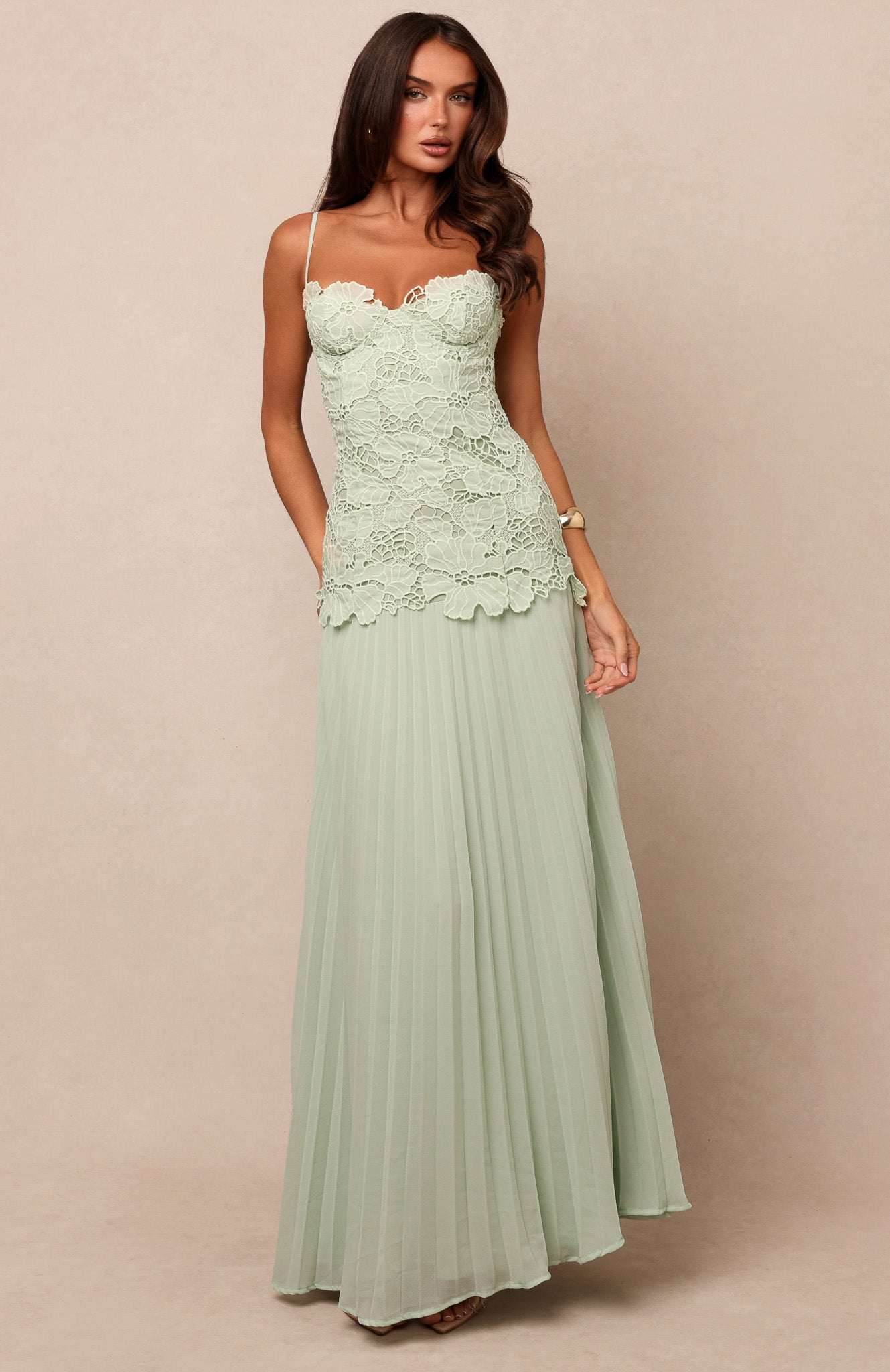 Featuring a sophisticated floral lace bustier bodice, intricate pleating, this gown is the ultimate statement choice for elevated vacation soirées.