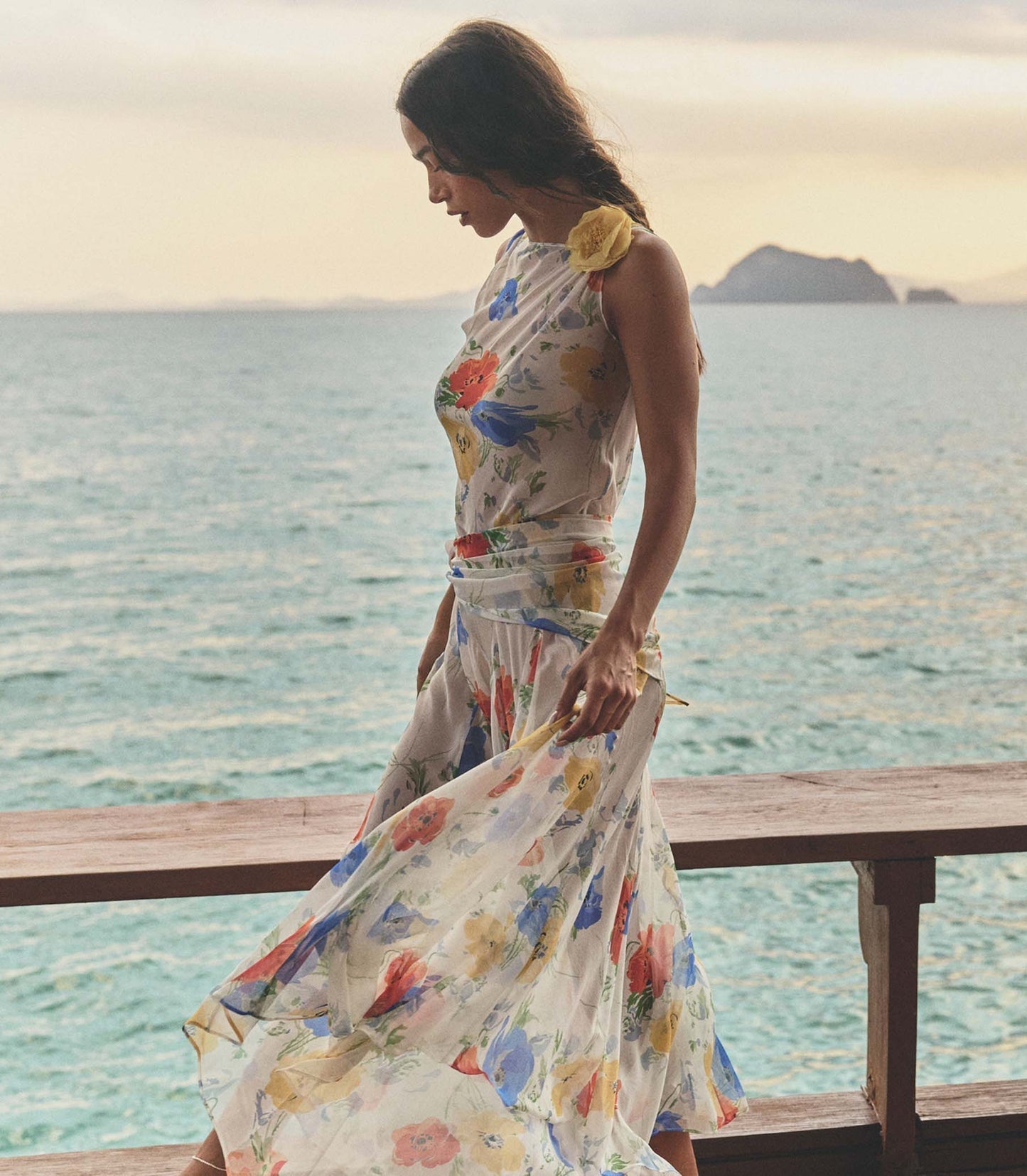 Featuring a vibrant watercolor floral prints, a delicate strap with yellow rosette, this maxi gown is the ultimate statement piece for luxury resort getaways.