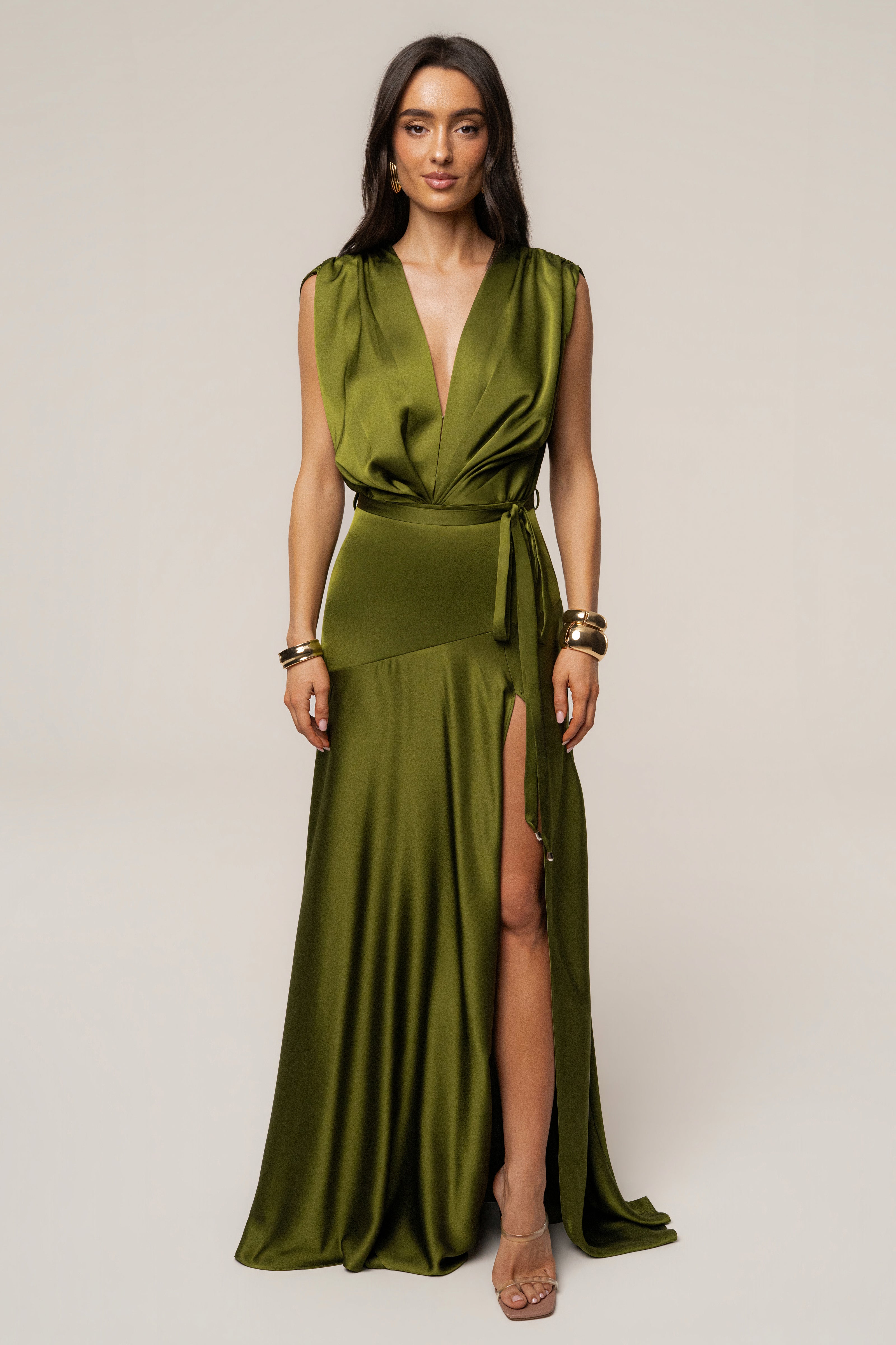Featuring a lustrous olive satin finish, a dramatic shoulder draping, a matching waist tie,this gown is the ultimate statement piece for luxury resort getaways.