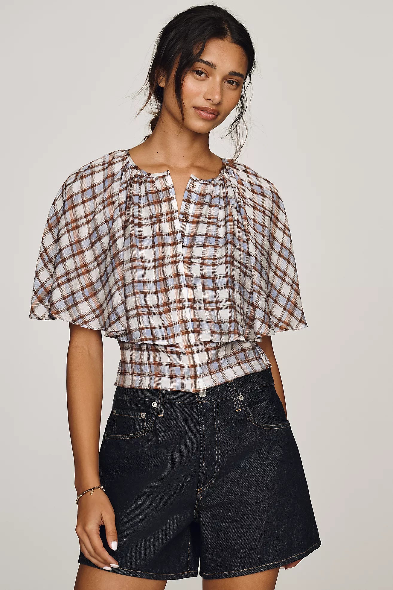 Featuring a creative layered capelet overlay design over a fitted bodice, this top is the ultimate statement piece for chic coastal getaways.