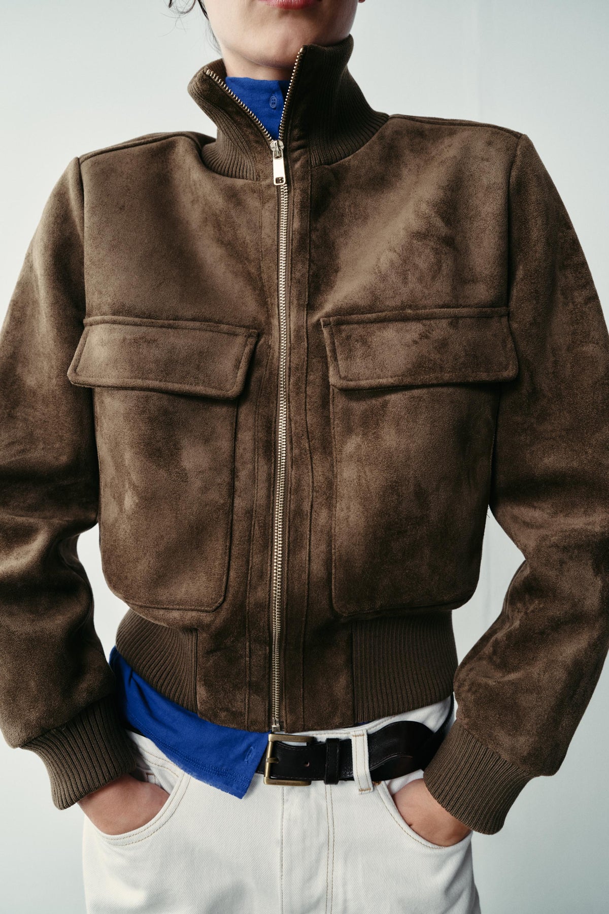 Featuring a structured mock neckline with a polished gold-tone zipper, dual chest flap pockets,this is the ultimate statement piece for transitional layering.