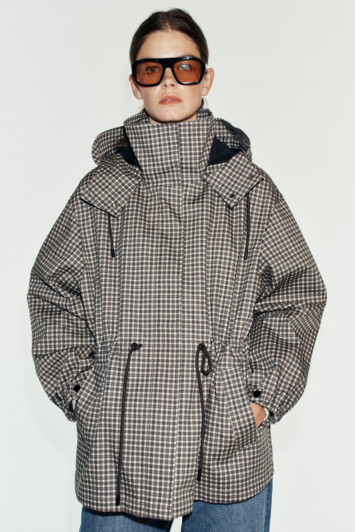Featuring a high-standing collar with an attached hood, adjustable waist drawstrings,this jacket is the ultimate statement piece for cool coastal getaways.
