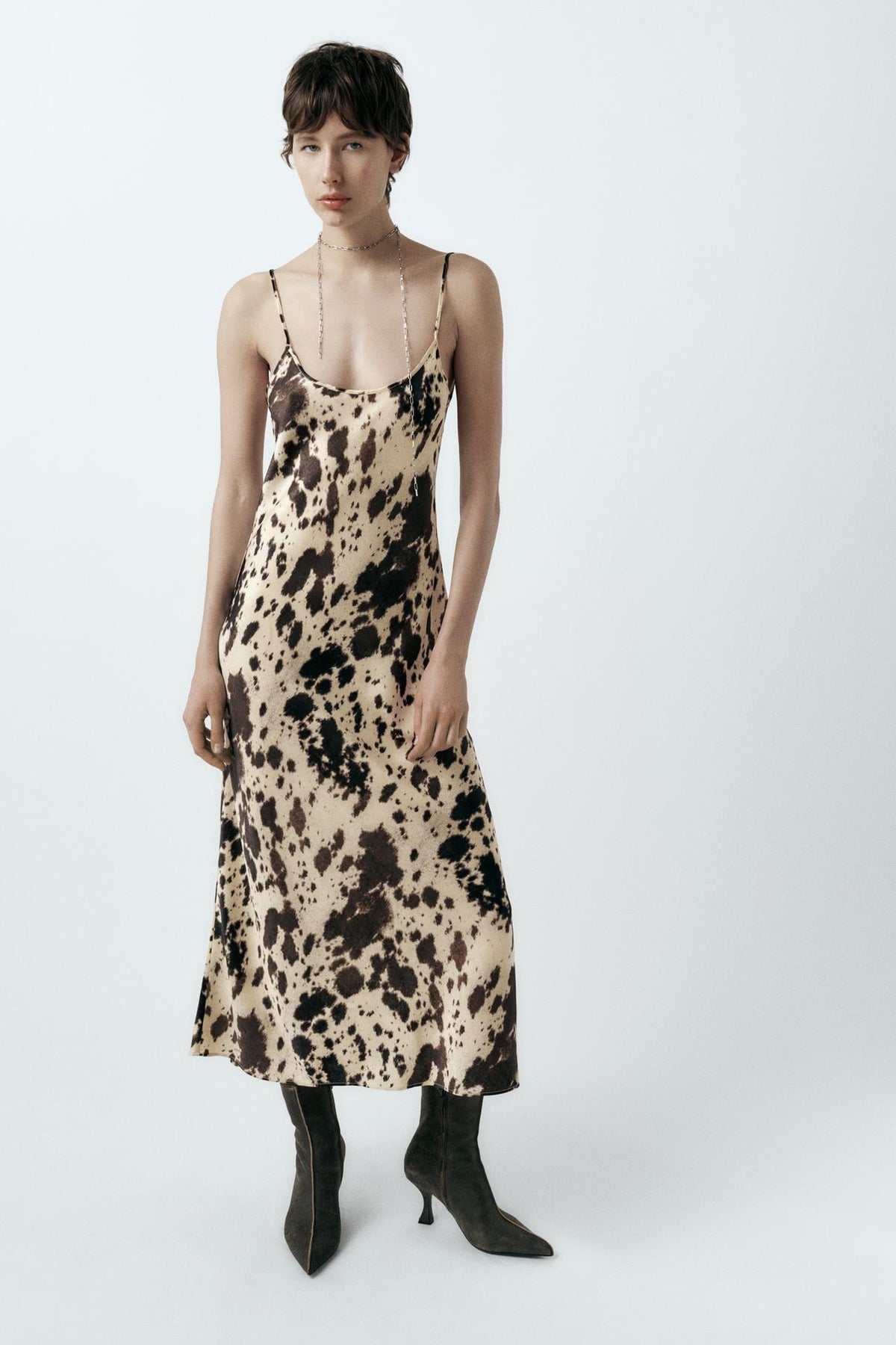 Featuring a brown and cream cow print, delicate spaghetti straps, this dress is the ultimate statement piece for luxury resort getaways.