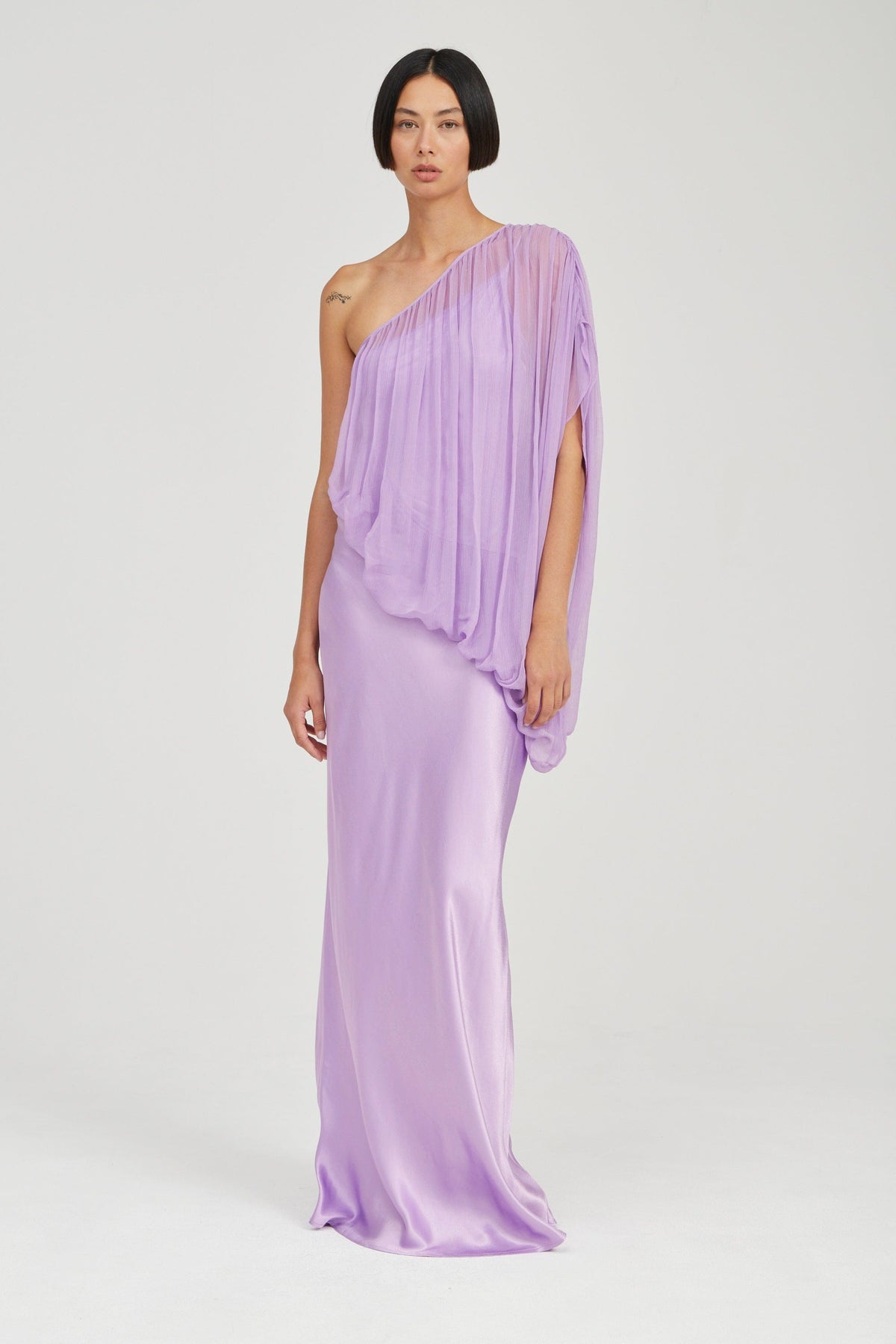 Featuring a slip base overlaid with a one-shoulder cape-like bodice, this dress is the ultimate statement piece for luxury resort getaways.