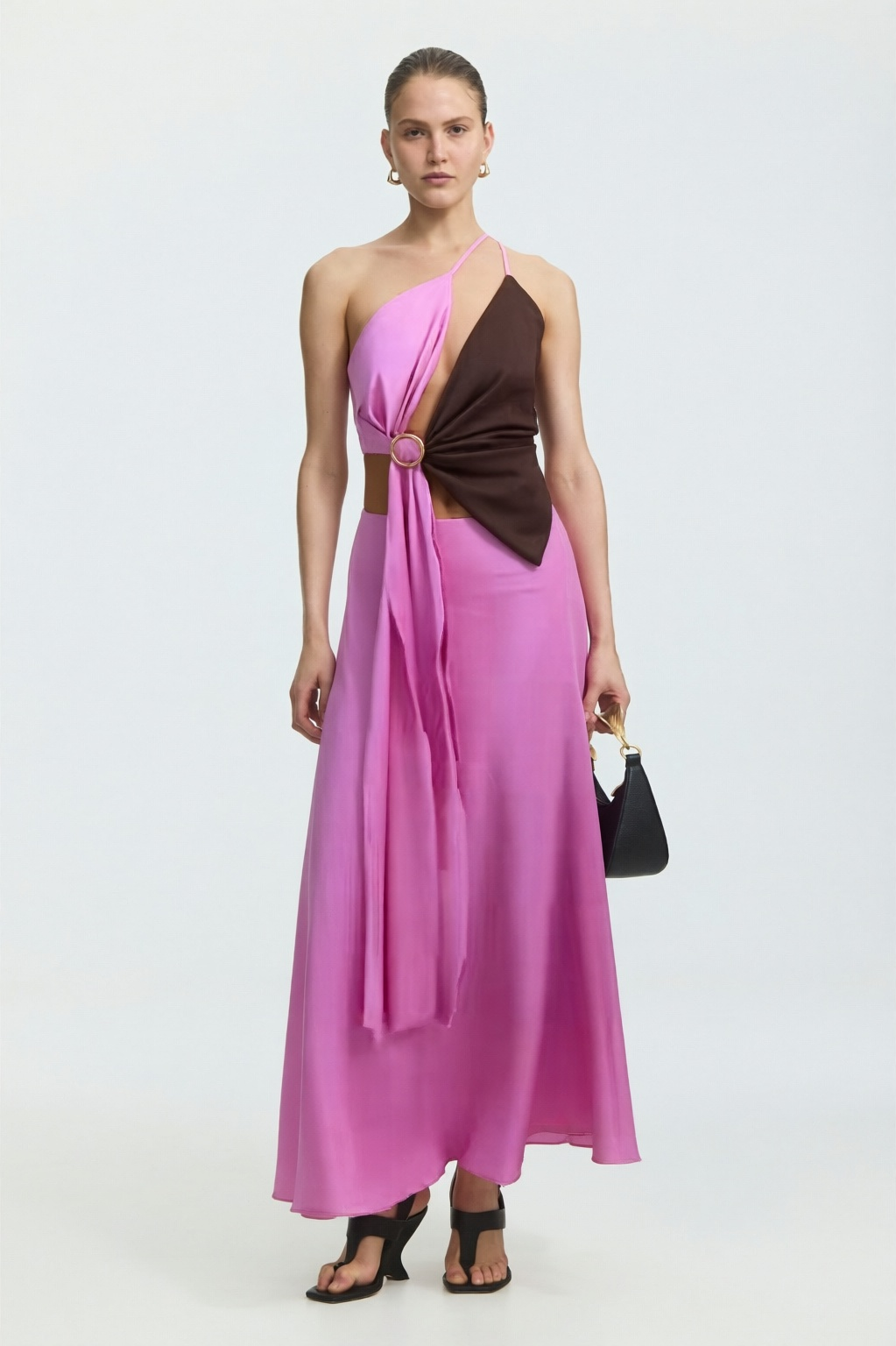 Featuring a asymmetric draped bodice connected by a metal ring, daring waist cut-outs,this dress is the ultimate statement piece for luxury resort getaways.
