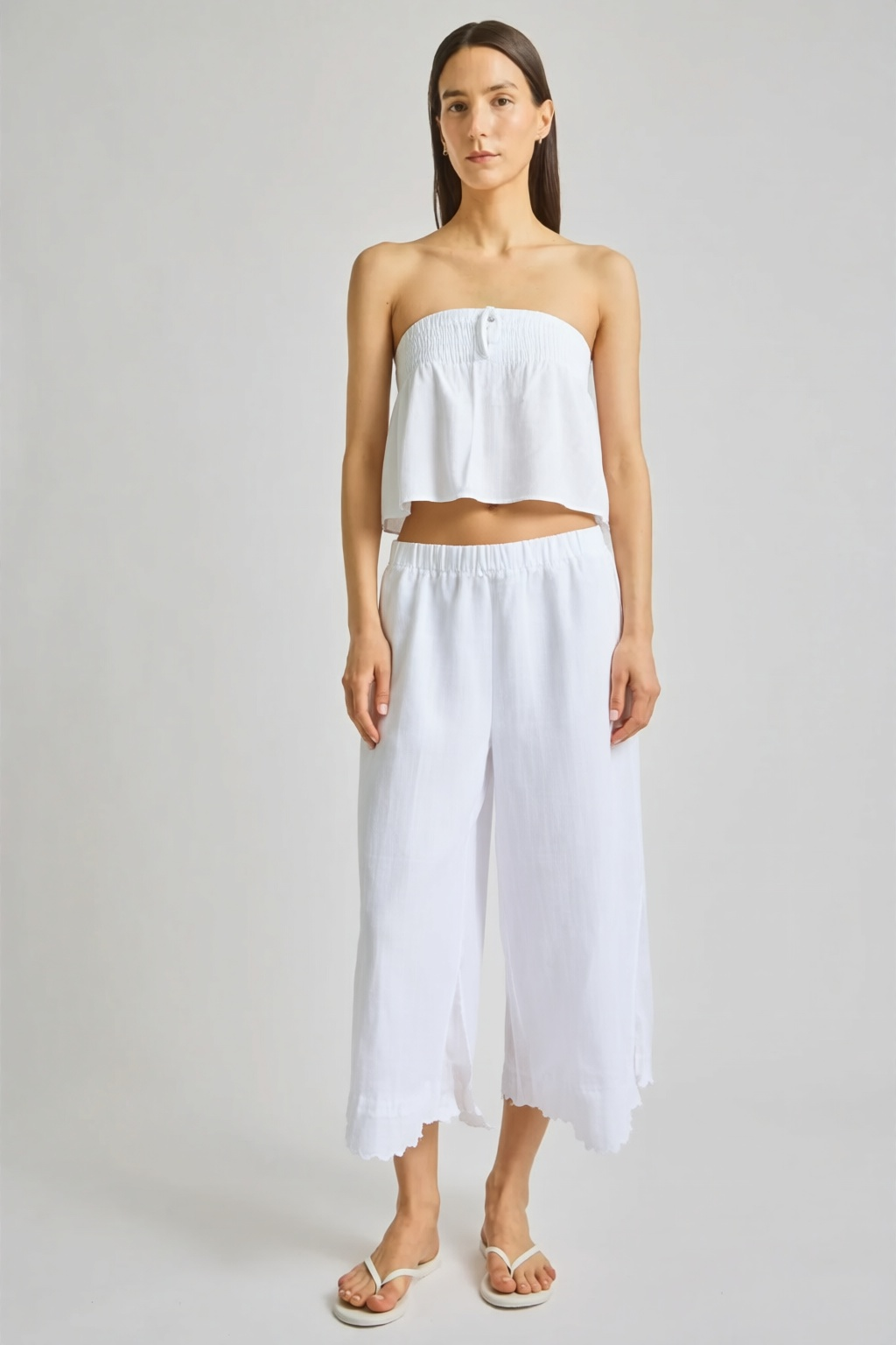 Featuring a pristine white smocked bandeau crop top and relaxed  with scalloped hems, this set is the ultimate statement piece for luxury resort getaways.