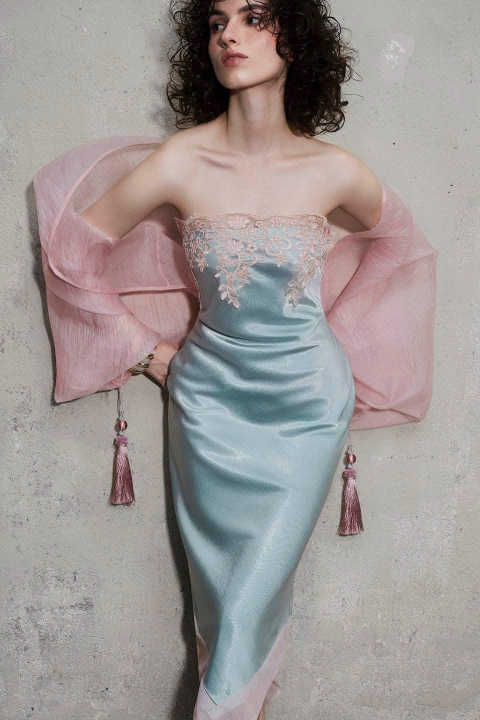 Featuring a pink lace embroidery along the strapless neckline, an asymmetric hemline, this dress is the ultimate statement piece for luxury resort getaways.