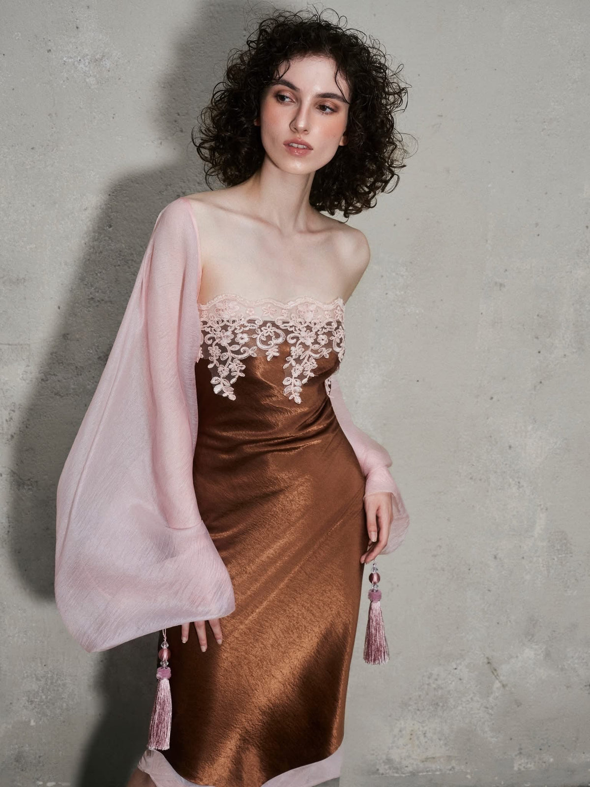 Featuring a pink lace embroidery along the strapless neckline, an asymmetric hemline, this dress is the ultimate statement piece for luxury resort getaways.