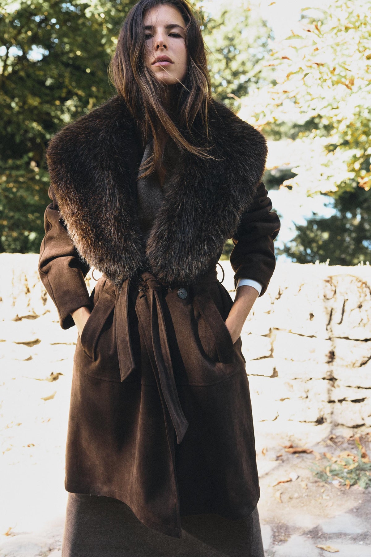 Featuring a dramatic plush faux-fur shawl collar, a cinching waist tie belt, this trench coat is the ultimate statement piece for luxury winter resort getaways.