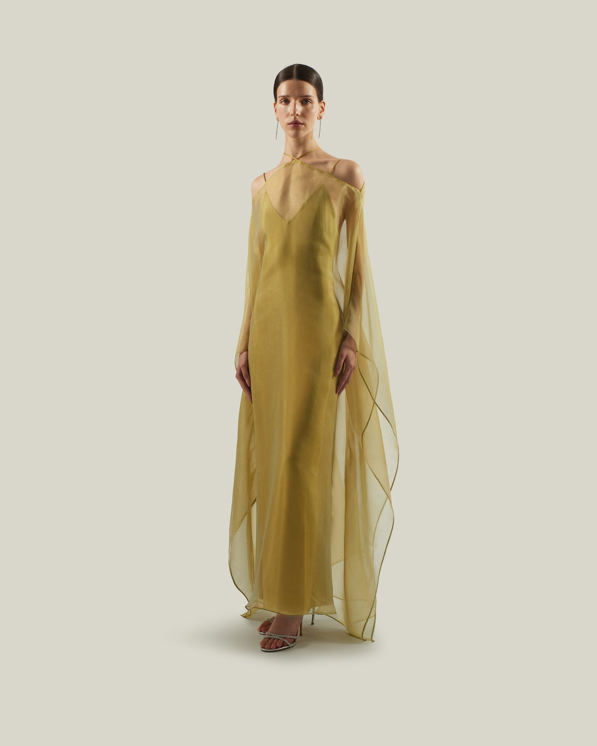 Featuring a slip dress with a sheer chiffon over-layer cape with a halter-tie neckline, this gown is the ultimate statement piece for luxury resort getaways.