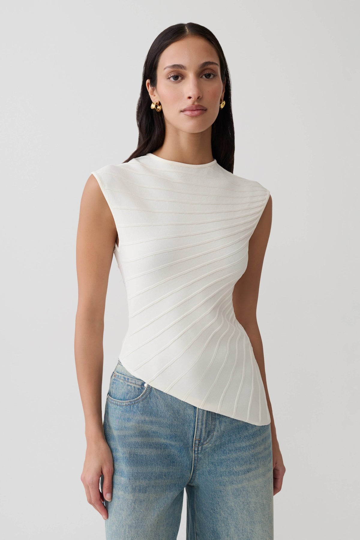 Elevate your wardrobe with the Seashellly Asymmetrical Diagonal Rib Sleeveless Knit Top. Featuring sculptural ribbing, cap sleeves and artful uneven hem. 